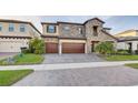 Beautiful two-story home boasts a stone front, three-car garage, and a meticulously paved driveway at 12857 Satin Lily Dr, Riverview, FL 33579