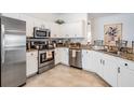 Well-lit kitchen featuring white cabinets, granite countertops, and stainless steel appliances at 13247 Palmilla Cir, Dade City, FL 33525