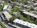 An aerial view highlighting the community pool, shuffleboard courts and building exteriors at 1375 Doolittle Ln # 103, Dunedin, FL 34698