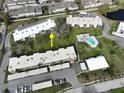 An aerial view showing the proximity of the swimming pool, common building and pond at 1375 Doolittle Ln # 103, Dunedin, FL 34698