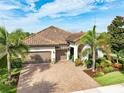 Aerial view of a single-story home with beautiful landscaping, brick driveway, tile roof, and an attached two-car garage at 14315 Rolling Dune Rd, Lithia, FL 33547