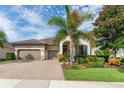 Inviting single-story home with a brick driveway, a two-car garage, and a beautifully landscaped front yard with lush greenery at 14315 Rolling Dune Rd, Lithia, FL 33547