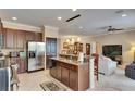 Open kitchen with stainless steel appliances, an island with breakfast bar, and dark wood cabinets at 144 Silver Falls, Apollo Beach, FL 33572