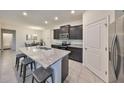 Stylish kitchen featuring a granite island with seating and dark cabinetry at 16611 Goose Ribbon Pl, Wimauma, FL 33598