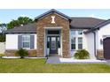 Charming home showcasing a stone facade and a decorative front door with elegant landscaping at 19730 Preservation Woods Dr, Lutz, FL 33558