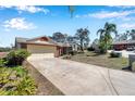 Exterior view featuring a long driveway leading to a two-car garage, surrounded by lush landscaping at 8137 Greenside Ln, Hudson, FL 34667