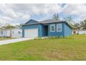 Blue single-story home featuring a garage, front lawn, and blue paint color at 9510 Xenia St, New Port Richey, FL 34654