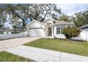 Charming single-story home with a brick driveway, lush lawn, and neutral-toned exterior paint at 3405 W Cherry St, Tampa, FL 33607