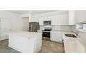 Modern kitchen featuring stainless steel appliances, white cabinets, and a spacious quartz island at 4275 Big Sky Dr, Spring Hill, FL 34604