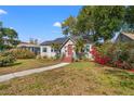 Charming bungalow-style home featuring a red front door, lush landscaping, and a curved walkway at 511 27Th N Ave, St Petersburg, FL 33704