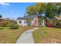 Charming bungalow-style home featuring a red front door, lush landscaping, and a curved walkway at 511 27Th N Ave, St Petersburg, FL 33704