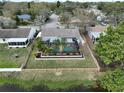 Aerial view of a private backyard featuring a screened-in pool, wood fence, and surrounding greenery at 641 Bay Lake Trl, Oldsmar, FL 34677