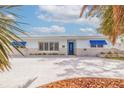 Inviting single-story home with a blue door, blue window awnings and meticulous landscaping at 7998 Causeway N Blvd, St Petersburg, FL 33707