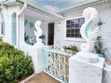 Inviting entryway with seahorse statues, blue gate, and coastal decorations that lead to a wood-paneled front door at 13801 Plumosa Ave, Hudson, FL 34667