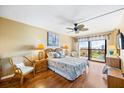 Bedroom with wood floors, ceiling fan, balcony, and ocean view at 1651 Sand Key Estates Ct # 53, Clearwater, FL 33767