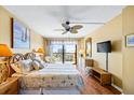 Bedroom with wood floors, ceiling fan, balcony, and ocean view at 1651 Sand Key Estates Ct # 53, Clearwater, FL 33767