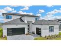 Modern home featuring a black garage door, monochromatic color scheme, and paver driveway at 32347 Wetland Bird Vw, San Antonio, FL 33576