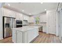 Bright white kitchen with stainless appliances, island, and wood floors at 9466 Shorebird Ct, Parrish, FL 34219