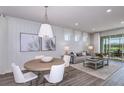 Open-concept living and dining area with wood-look floors, white shiplap accents, and sliding glass doors to the patio at 9470 Shorebird Ct, Parrish, FL 34219