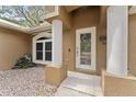 Inviting entryway featuring decorative pillars, an arched window, rock garden and a tiled walkway at 1185 Sanger Ave, Spring Hill, FL 34608