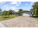 Paver driveway leads to a well-maintained home with a two-car garage, palm trees, and landscaped yard at 2037 Church Creek Pt, Largo, FL 33774