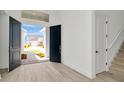 Bright foyer with wood floors, a staircase, and double doors leading to a paved walkway surrounded by landscape at 32335 Wetland Bird Vw, San Antonio, FL 33576