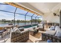 Inviting outdoor patio with comfortable seating, a dining table, and a summer kitchen overlooking a lake at 33899 Astoria Cir, Wesley Chapel, FL 33545