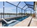 A stunning pool with a slide and water features, enclosed in a screened patio overlooking a lake at 33899 Astoria Cir, Wesley Chapel, FL 33545