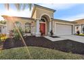 Inviting home exterior showcases lush landscaping, an arched doorway, and an attached two-car garage at 4145 Medbury Dr, Wesley Chapel, FL 33543