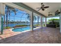 Enclosed, covered pool with a hot tub, ceiling fans, and brick pavers, all overlooking the waterfront at 5321 Fishersound Ln, Apollo Beach, FL 33572