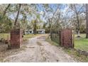 Gated driveway entrance to home featuring brick pillars, and a secure, elegant wrought iron gate at 5419 Cyril Dr, Dade City, FL 33523