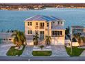 Waterfront home with a metal roof, featuring a multi-level exterior and an elegant stairway to the front door at 6976 S Shore S Dr, St Petersburg, FL 33707
