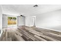 Bright living room showcasing new vinyl floors, fresh paint, modern ceiling fan and a sliding door to the backyard at 9331 Crabtree Ln, Port Richey, FL 34668