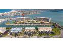 Aerial view showcasing waterfront condos, boat docks, pool, and tennis court near the bay at 1 Key Capri # 604W, Treasure Island, FL 33706