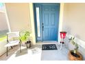 Cozy front porch with stylish blue door, plant decor, and a 'Home' welcome mat at 12652 Chenwood Ave, Hudson, FL 34669