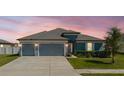 Inviting two-car garage home with neatly trimmed landscaping and a freshly paved driveway beneath a vibrant, colorful sky at 12749 Weatherstone Dr, Spring Hill, FL 34609