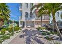 Coastal townhome boasts a brick-paved driveway, garage, and lush tropical landscaping at 140 Brightwater Dr # 1, Clearwater Beach, FL 33767