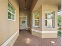 Inviting covered front porch with brick-paved flooring, double doors, and large white framed windows at 15908 Cobble Mill Dr, Wimauma, FL 33598