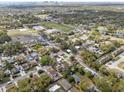 An aerial view shows the property in a neighborhood with mature trees, a school and a park with a pond nearby at 2401 E Cayuga St, Tampa, FL 33610