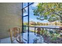 Relaxing patio with glass table and pineapple chairs overlooking a serene lake with a fountain feature at 2537 Gloriosa Dr # 2, Palm Harbor, FL 34684