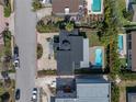 Aerial view of the home with a pool, dark roof, brick driveway, and lush landscaping in the backyard at 289 8Th N Ave, Tierra Verde, FL 33715