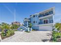 Stylish blue home with multiple balconies, a brick driveway, and a two-car garage, surrounded by lush landscaping at 289 8Th N Ave, Tierra Verde, FL 33715