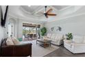 Bright living room with modern decor, ceiling fan, and sliding glass doors leading to outdoor dining area at 135 Cabana Way, Rotonda West, FL 33947