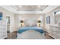 A bright main bedroom with white furniture and tray ceilings provides a restful and elegant retreat at 135 Cabana Way, Rotonda West, FL 33947