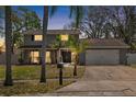 Charming two-story home at dusk features a well-maintained lawn, a two-car garage, and tasteful landscaping at 15802 Knollview Dr, Tampa, FL 33624