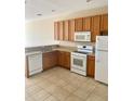 Bright kitchen with wood cabinets, white appliances, and tile flooring at 1973 Hawks View Dr, Ruskin, FL 33570