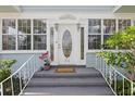Close-up of the front door with decorative glass, flanked by sidelights and sconces, set within a light blue home facade at 210 15Th N Ave, St Petersburg, FL 33704