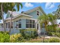 A light blue two-story home showcases a manicured lawn and charming exterior features, including many windows and palm trees at 210 15Th N Ave, St Petersburg, FL 33704