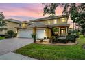 Elegant two-story home featuring a three-car garage, well-manicured lawn, and a beautiful front entrance at 2665 Lakebreeze N Ln, Clearwater, FL 33759