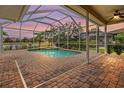 Relaxing screened-in pool area with brick pavers, offering a serene view of the lake at 2665 Lakebreeze N Ln, Clearwater, FL 33759